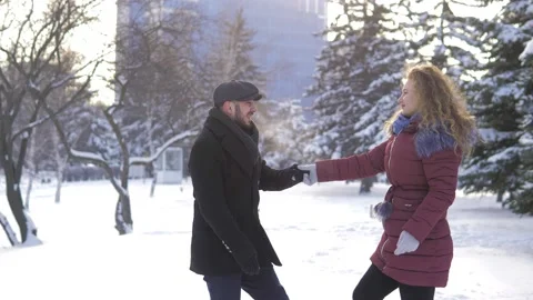 A happy couple playfully spends time in a winter park having fun on a snowy Stock Footage 162664336