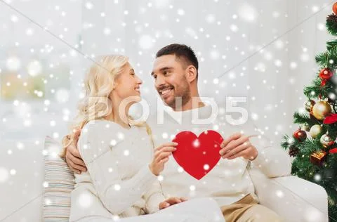 Happy couple with red heart at home for christmas Stock Photos