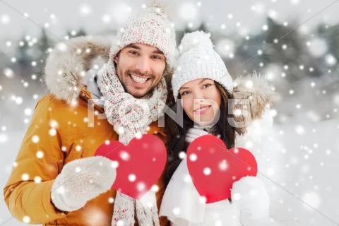 Happy couple with red hearts over winter landscape Stock Photos