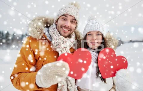 Happy couple with red hearts over winter landscape Stock Photos