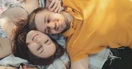 Happy Couple Relaxing On A Green Grass, Top View. Slow Motion 4K. Young Family Stock Footage