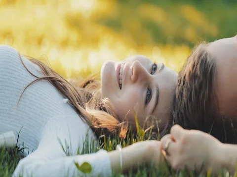 Happy Couple Relaxing on a Green Grass. SLOW MOTION 4K. Young Family Stock Footage
