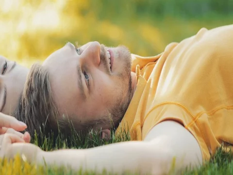Happy Couple Relaxing on a Green Grass. SLOW MOTION 4K. Young Family Stock Footage