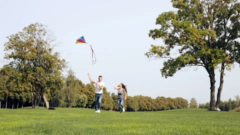 Happy couple running, having fun and playing with kite in the park. Stock Footage 95482080