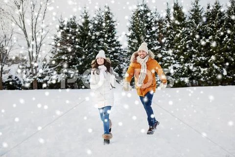 Happy couple running in winter snow Stock Photos