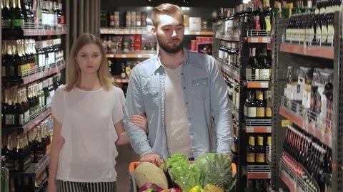 Happy couple selecting drinks in a vibrant hypermarket aisle Stock Footage 311820905