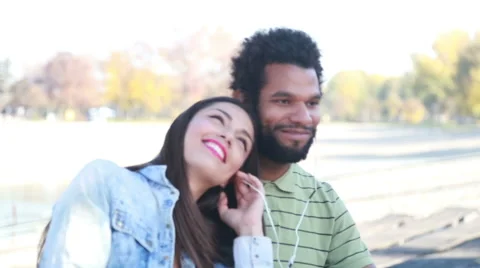 Happy couple with shared earphones listening to music and enjoying Stock Footage 59555093