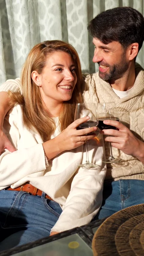 Happy couple sharing wine and laughter on sofa Stock Footage 303554687