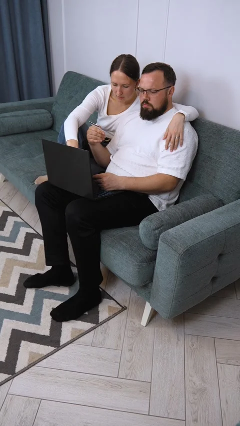 Happy couple shopping online using laptop and credit card on sofa Stock Footage 320500565