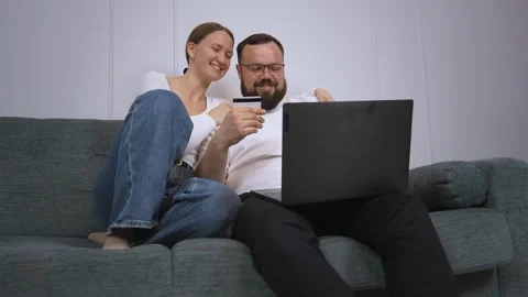 Happy couple shopping online using laptop and credit card on sofa Video stock 320501650