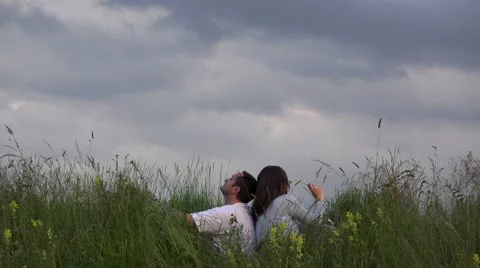 Happy couple sitting back to back on spring field close sky, smile, vacation 4K Stock Footage 46206312