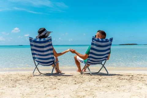 Happy couple is sitting in chairs on a tropical beach. Summer vacation concep Stock Photos