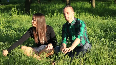 Happy couple sitting on the grass and smile 動画素材 33953678