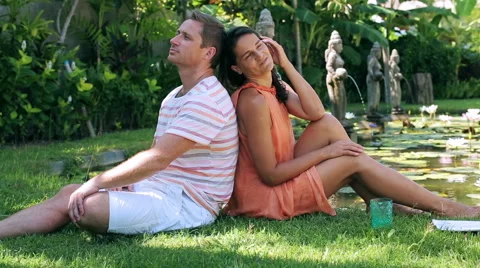 Happy couple sitting on grass and smiling to the camera Stock-Footage 40323402