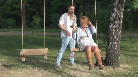 Happy couple sitting in a swing Vídeos de archivo 23748597