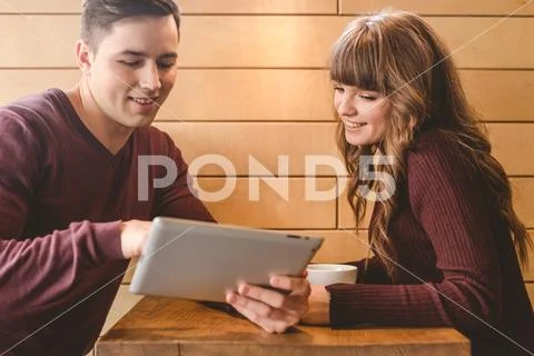 The happy couple sitting with a tablet at the restaurant table Stock Photos
