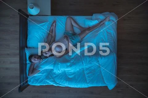 The happy couple sleeping on the bed. evening night time. view from above Stock Photos