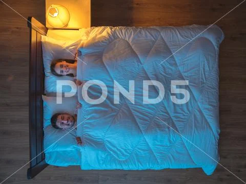 The happy couple sleeping on the bed. evening night time. view from above Stock Photos