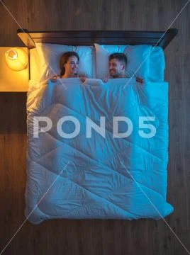 The happy couple sleeping on the bed. evening night time. view from above Stock Photos