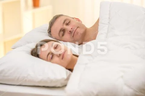 The happy couple sleeping on the bed Stock Photos