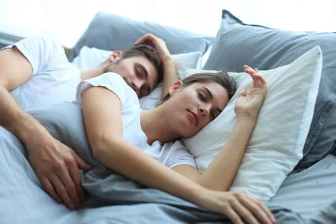 Happy couple sleeping in a comfortable bed at home. Stock Photos