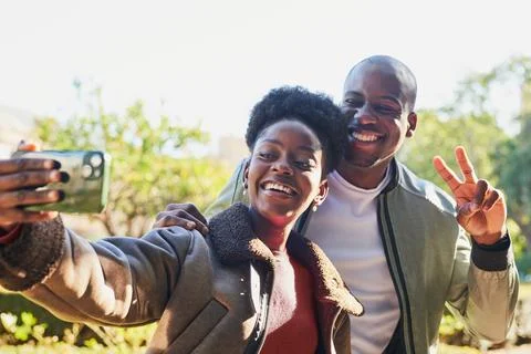 Happy Couple Smiling While Taking a Selfie Outdoors in Bright Sunlight Foto stock