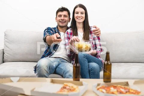 The happy couple on the sofa watching television on the white wall background Stock Photos