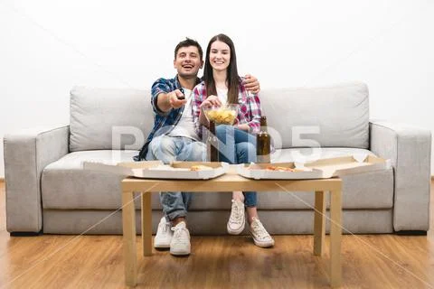The happy couple on the sofa watching tv on the white wall background Stock Photos