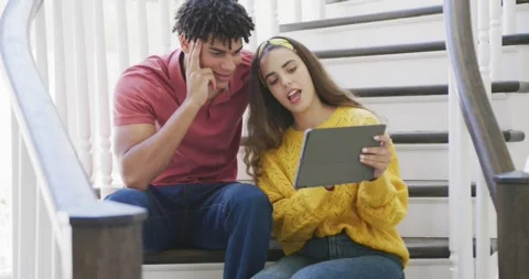 Happy couple spending time at home using tablet and sitting on stairs Stock Footage 344849708
