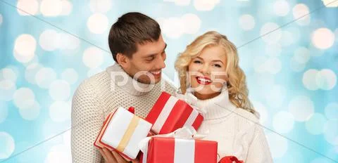 Happy couple in sweaters holding christmas gifts Stock Photos