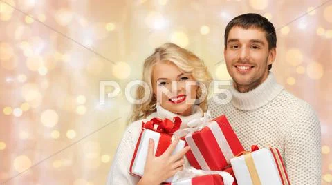 Happy couple in sweaters holding christmas gifts Stock Photos