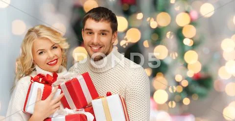 Happy couple in sweaters holding christmas gifts Stock Photos