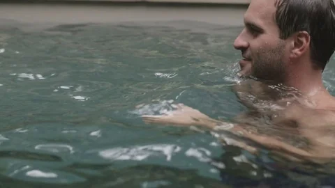 Happy couple swims and kisses in the pool Stock Footage