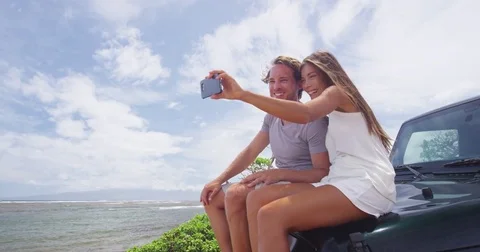 Happy Couple Taking Selfie Using Smartphone On SUV Car At Shipwreck Beach Lanai Stock Footage 78890267