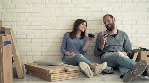 Happy  couple talking and drinking wine on floor at their new home Stock Footage 65381155