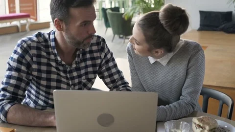 Happy couple talking and using laptop during lunch at cafe Stock Footage 70808502