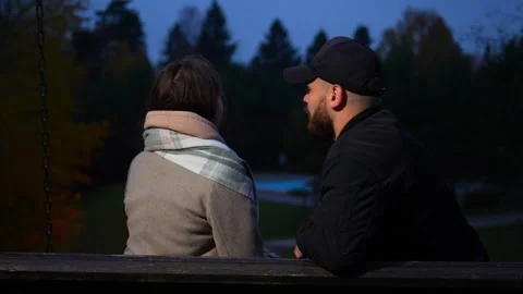 Happy couple talking together swinging on swings outdoors in autumn park Video stock 254004853