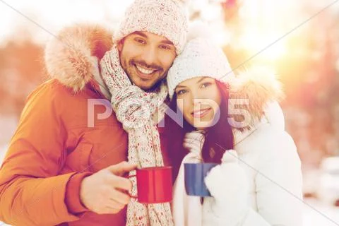Happy couple with tea cups over winter landscape Stock Photos