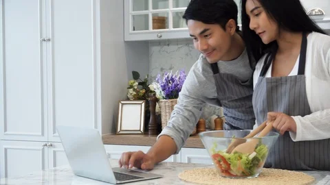 The happy couple use laptop computer while cooking in kitchen Stock Footage 87489807