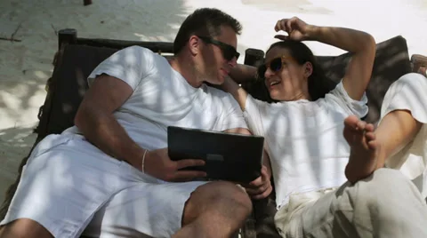 Happy couple using laptop and lying on sunbeds, steadycam shot Stock Footage 39216301