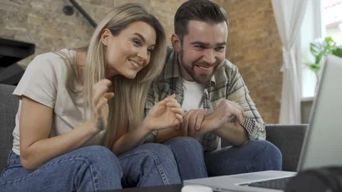 Happy couple using laptop for video call in the living room Video stock 233430262