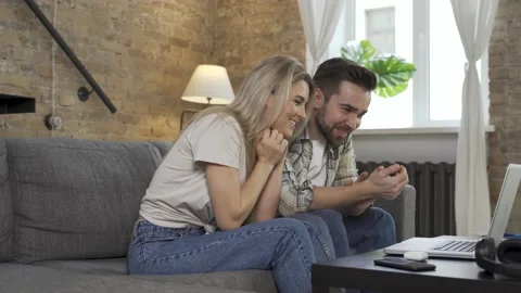 Happy couple using laptop for video call in the living room Video stock 233430408