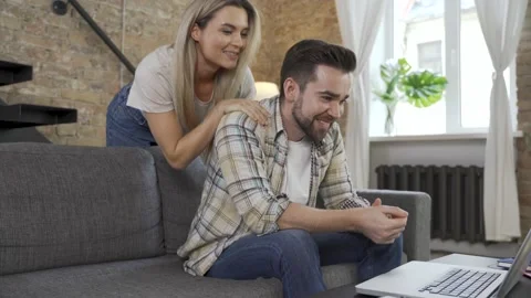 Happy couple using laptop for video call in the living room Video stock 233431870