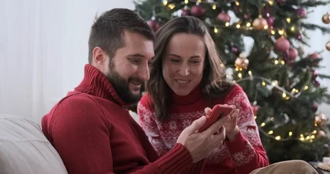 Happy couple using mobile phone during Christmas at home Stock Footage 129425224