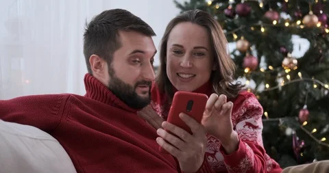 Happy couple using mobile phone and credit card for Christmas shopping 스톡 동영상 129425472