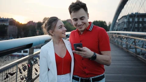 Happy couple using smartphone on bridge in city smile attractive beautiful Stock Footage 95450016