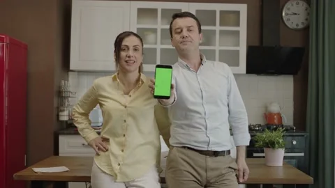 Happy couple using smartphone at dining table in kitchen Stock Footage 203534358