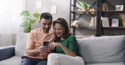 Happy couple using smartphone, shopping online, ordering delivery, planning Stock Footage 266838137