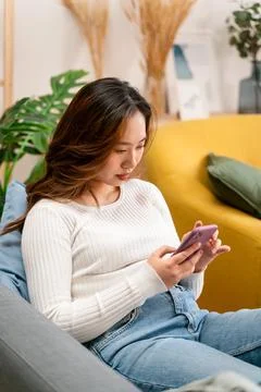 Happy couple using smartphone on sofa Stock Photos