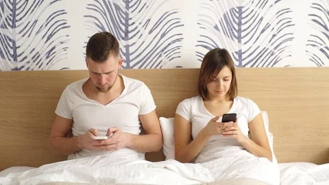 Happy couple using social networking with their phones in the bed Stock Footage 73995831